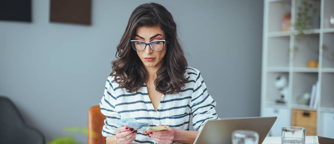 Woman wearing fashionable glasses counts money.