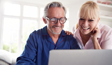 Mature Couple At Home Looking Up Information Using Laptop.