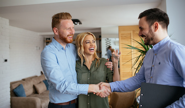 Portrait of financial adviser congratulating a young couple for buying a new house.
