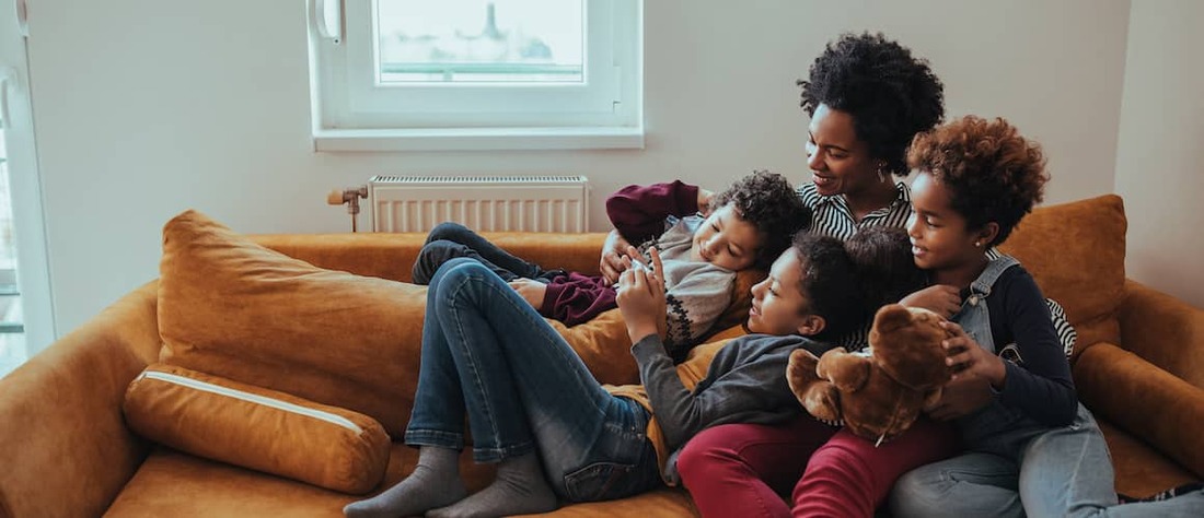 Family cozied up on a couch together.