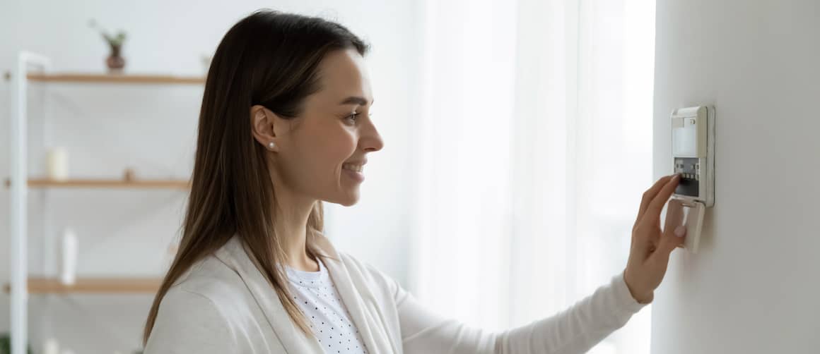 Woman using thermostat in new home.